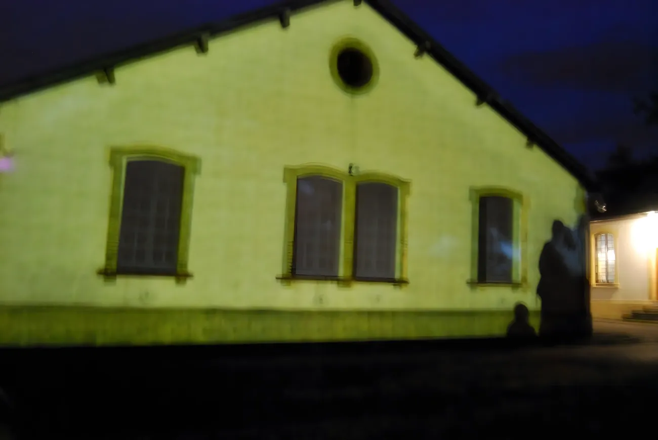 Projection mapped onto a Royallieu barrack facade in green light